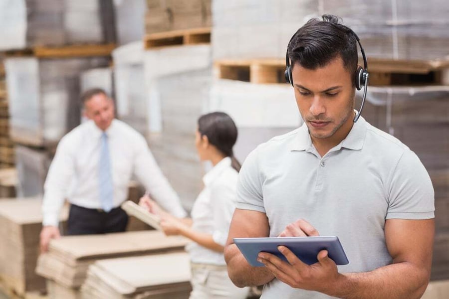 Morgan team member reviewing shipment data on a tablet in a warehouse