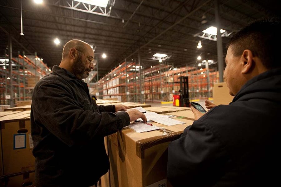 Morgan team members verifying shipment paperwork in a warehouse